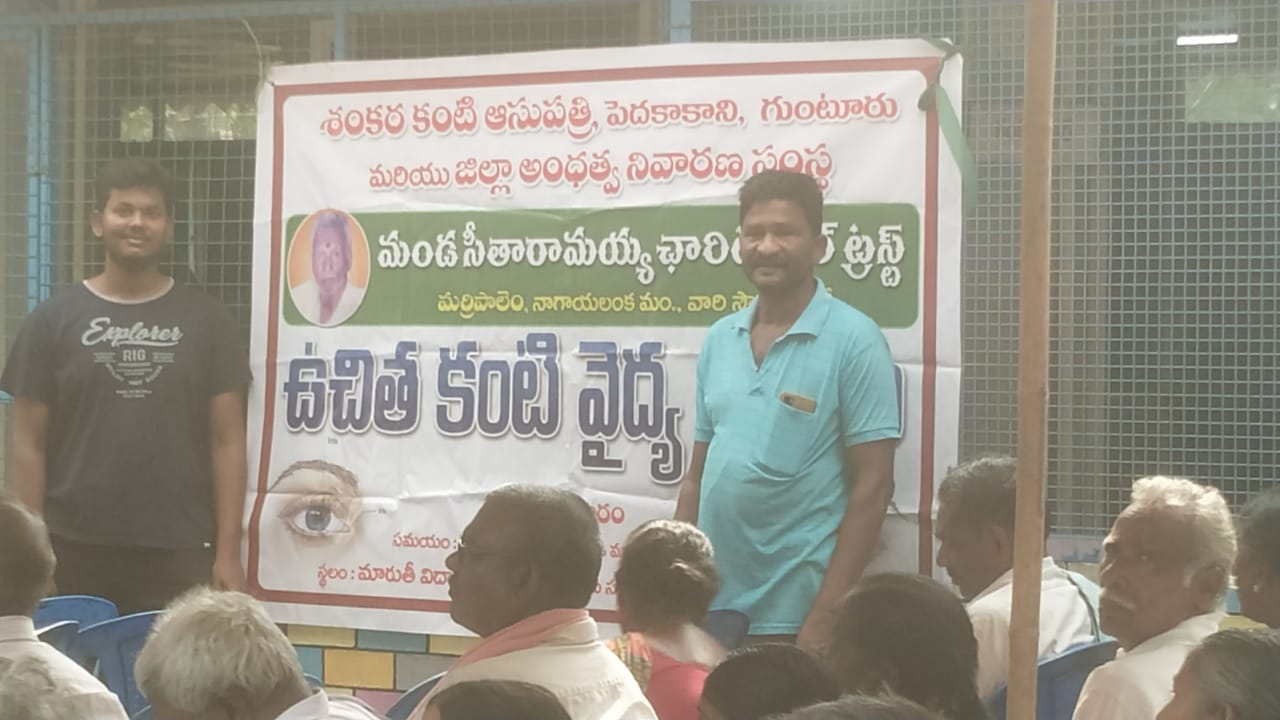 Trust volunteers standing beside the free eye care camp banner at the venue